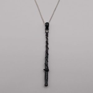 Dije de varita mágica pavonada con piedra